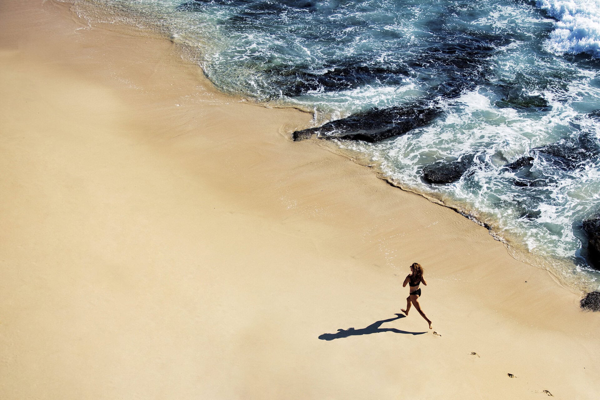 Beautiful girl walks along the wild beach